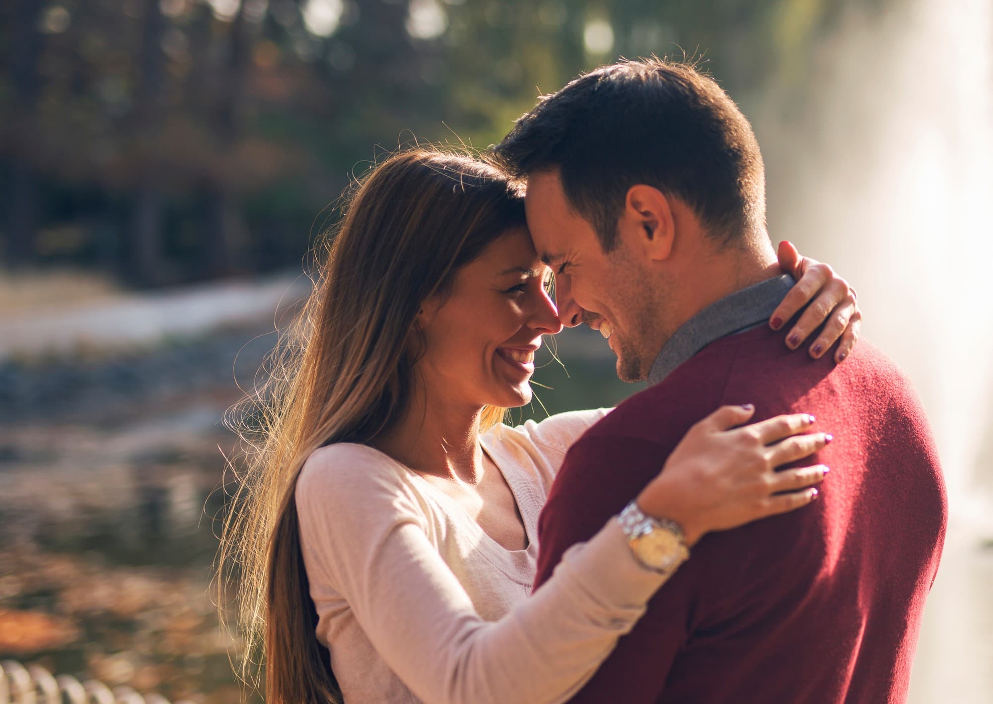 A couple smiling with foreheads together, embracing outdoors